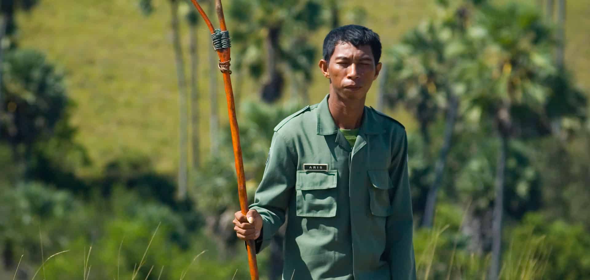 A portrait of a Komodo Ranger called Aris in green, luscious hills of Komodo