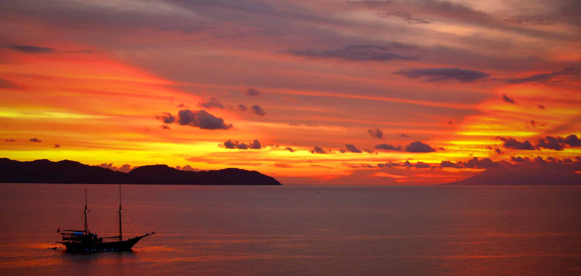 Orange sunset skies over Dunia Baru anchored near Komodo