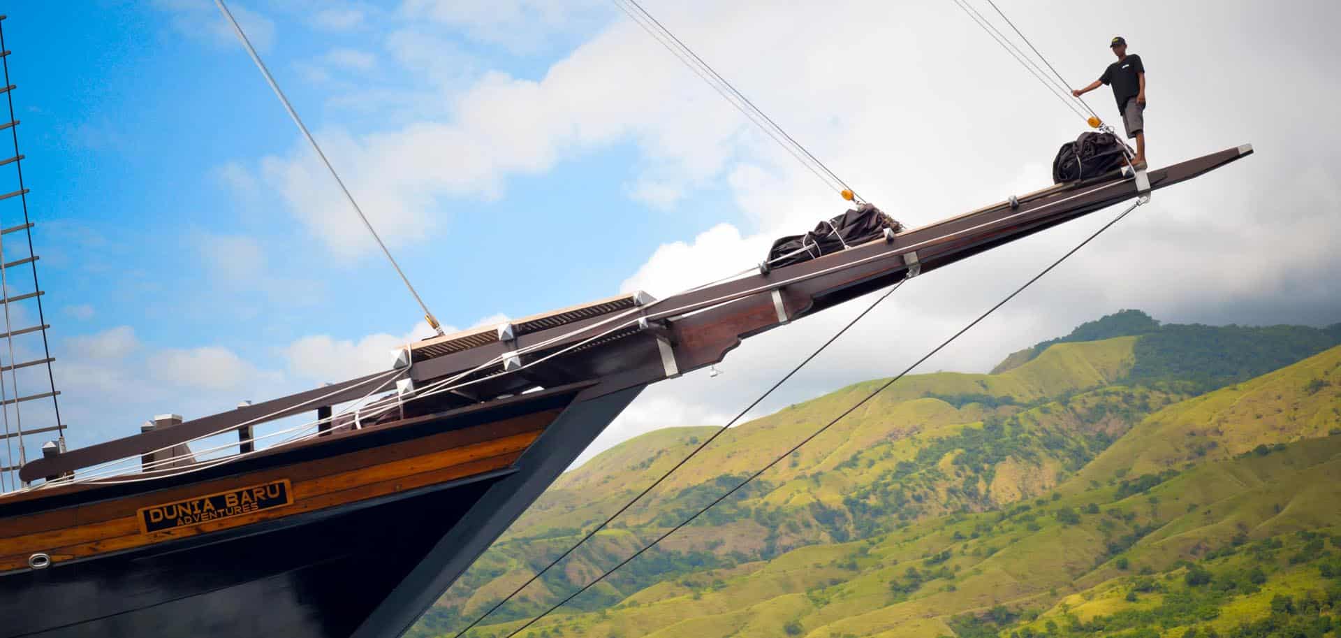 A crew member of Dunia Baru standing on the wooden bow of the super yacht