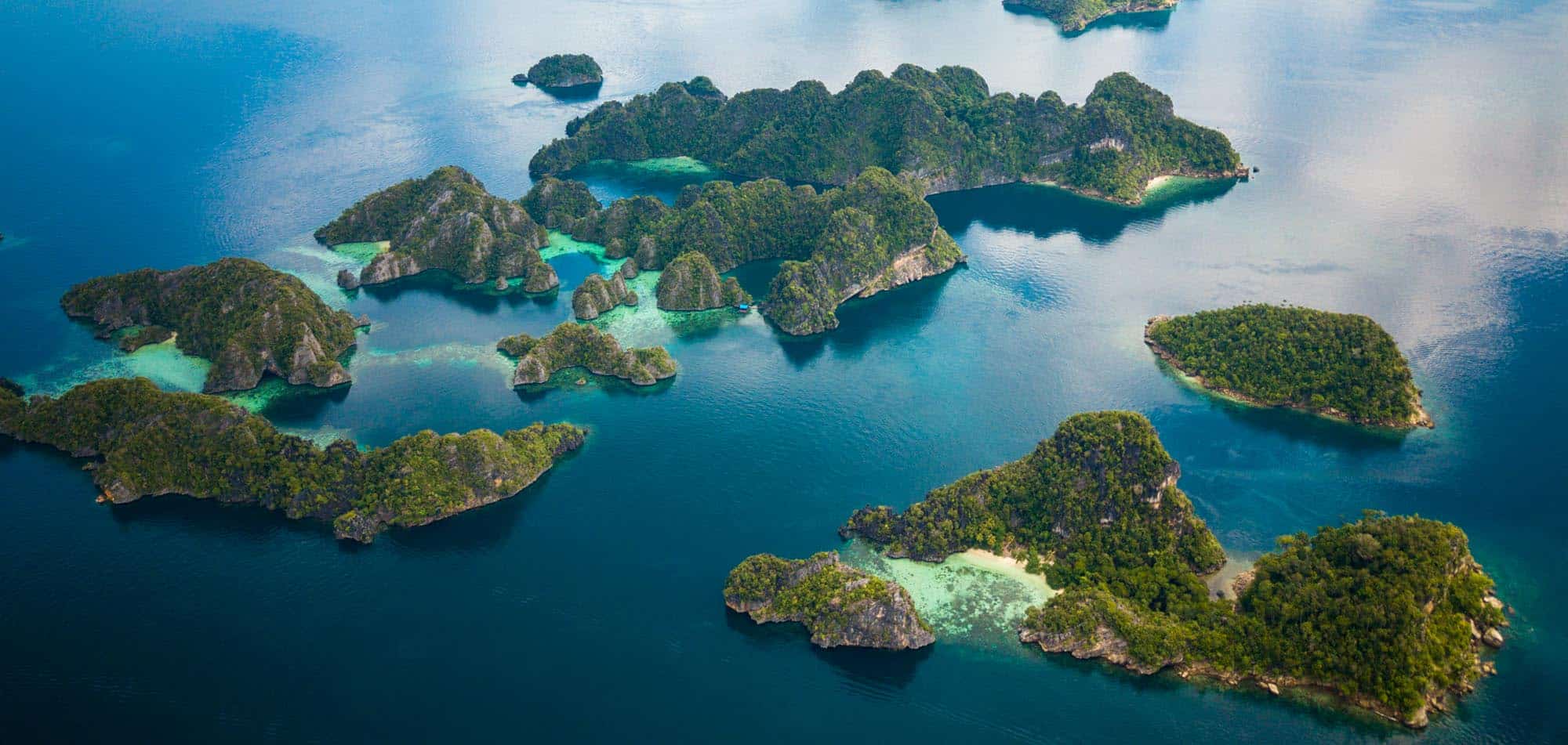 Aerial view of Raja Ampat's emerald green islands where only private yacht charters go