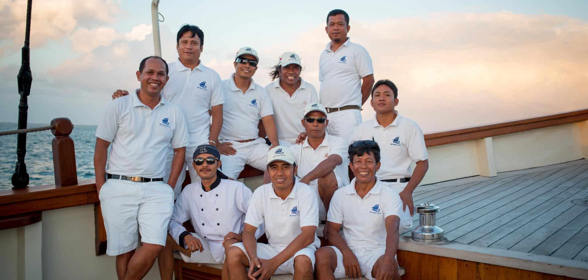 Group of Indonesians from Mutiara Laut's yacht crew smiling and posing for a photograph