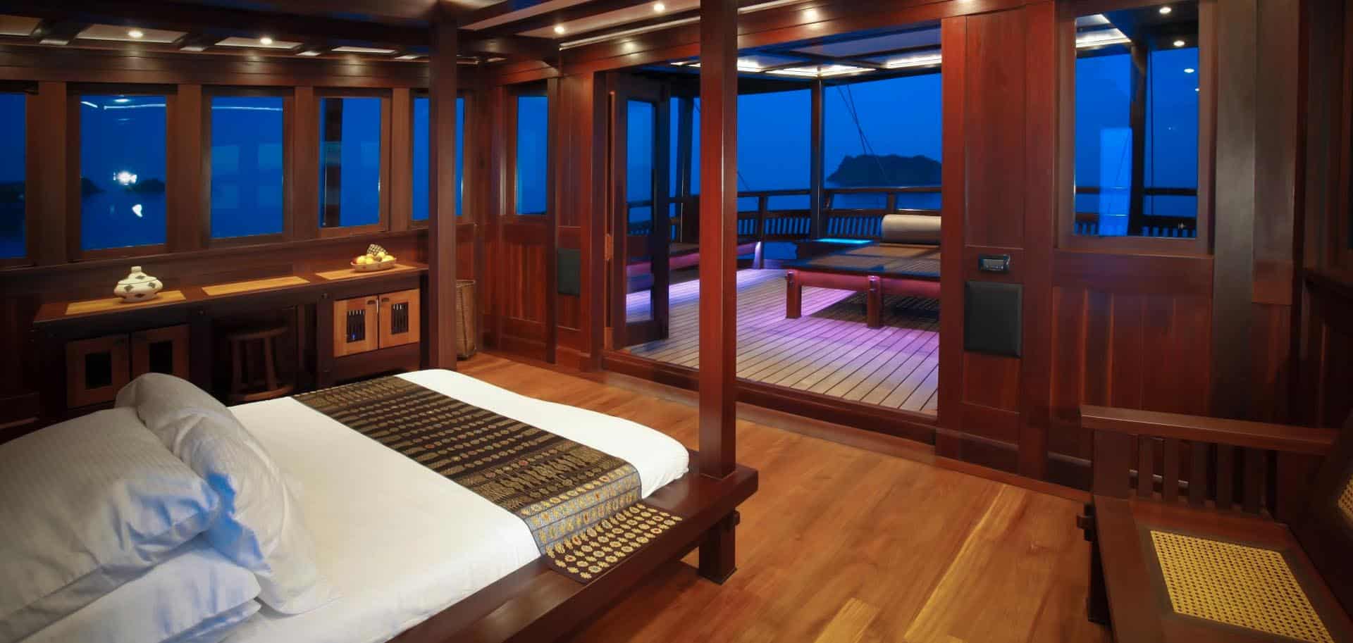 Wooden luxurious bedroom with a door open to the outside on deck of Dunia Baru