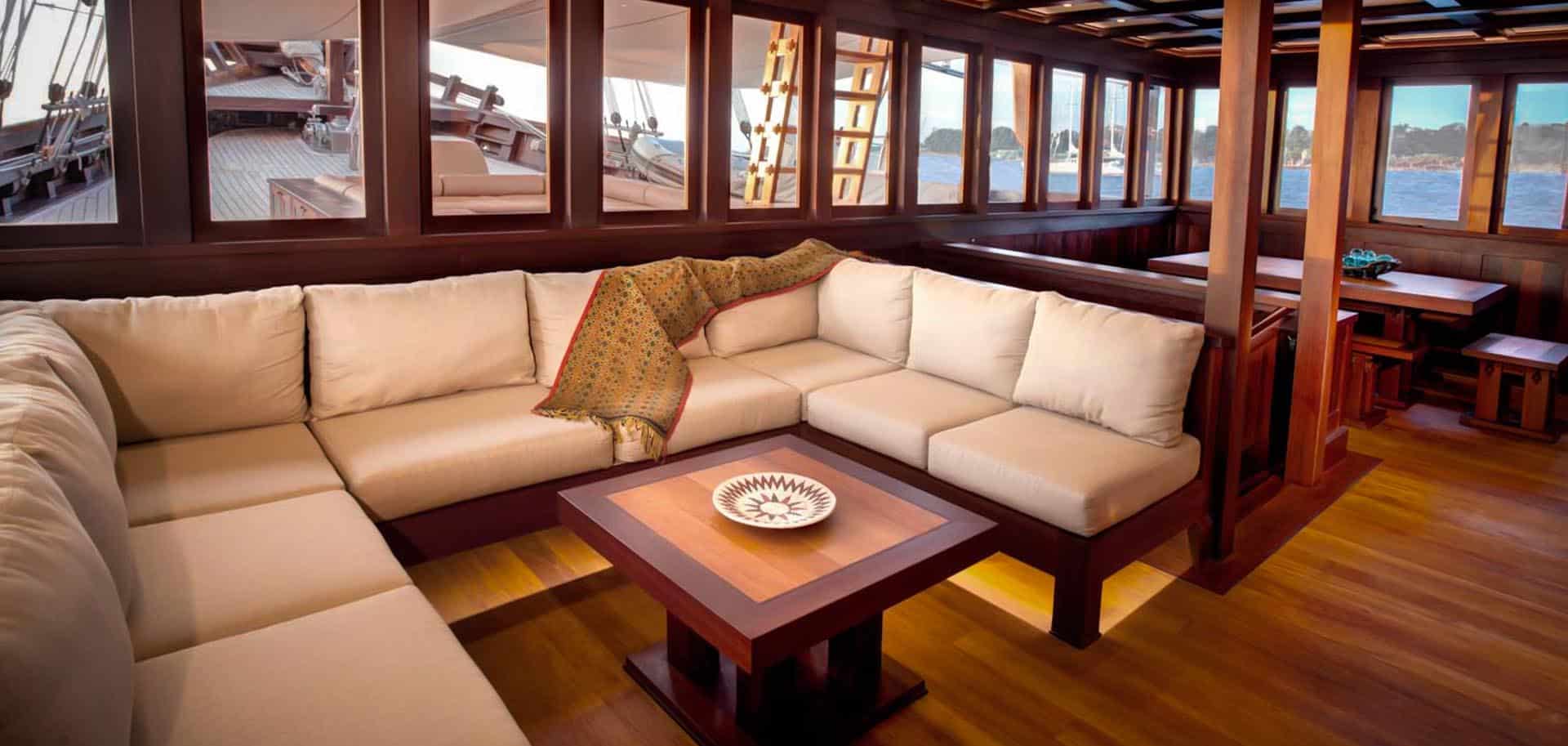 Spacious lounge area of Dunia Baru's interior with creamy white sofa pillows and wooden furniture