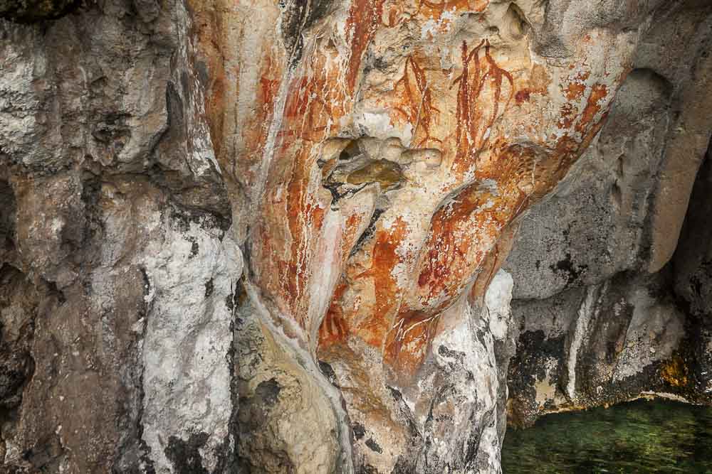 Close up on rocky walls of a cave with primitive paintings