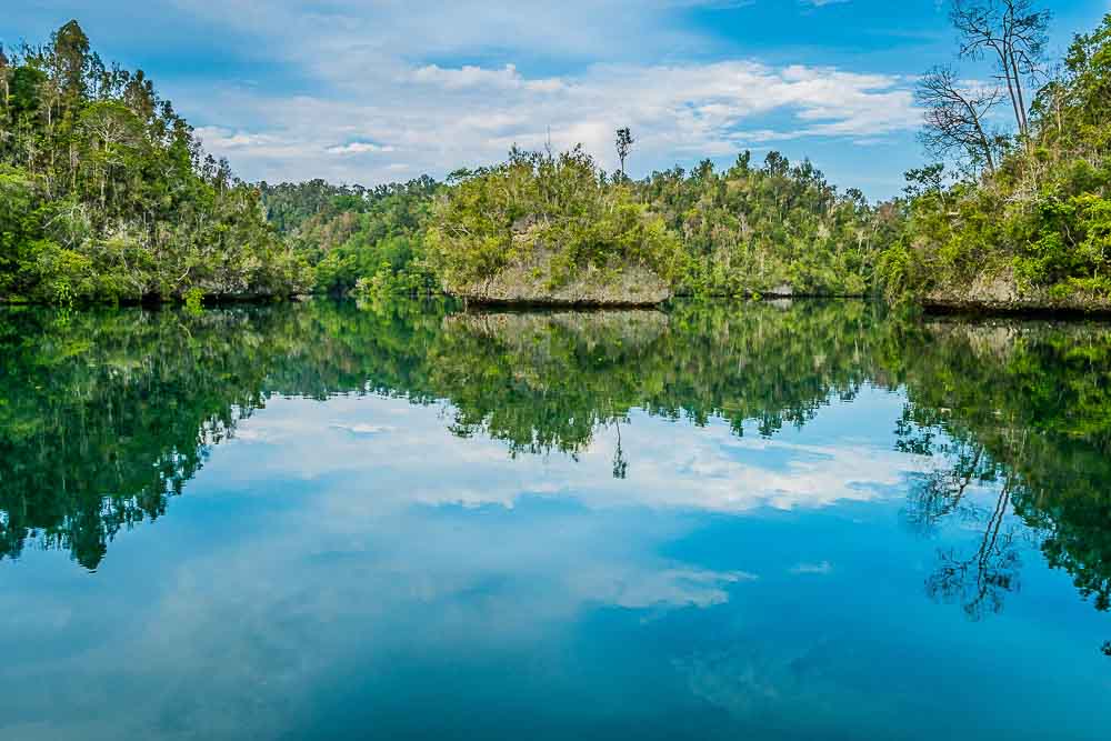 Green islands of Penemu reflected in crystal clear water