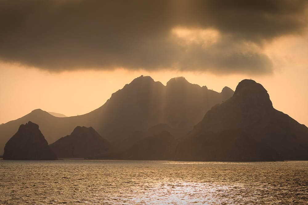 Yellow skies illuminated in waters near Nusa Kode in Komodo National Park, with mountainous islands in the background