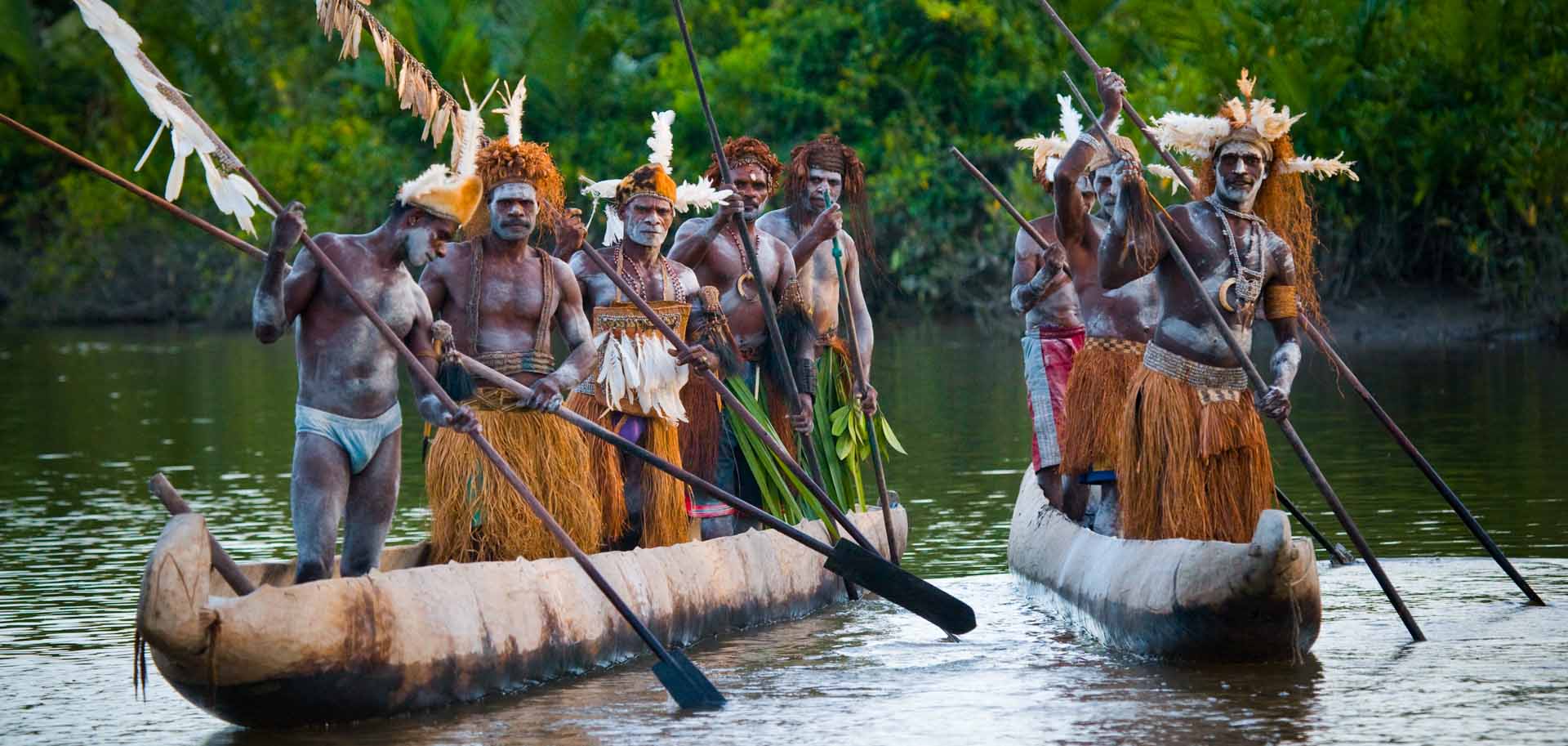 Tribe of native West Papuans rowing on two canoes