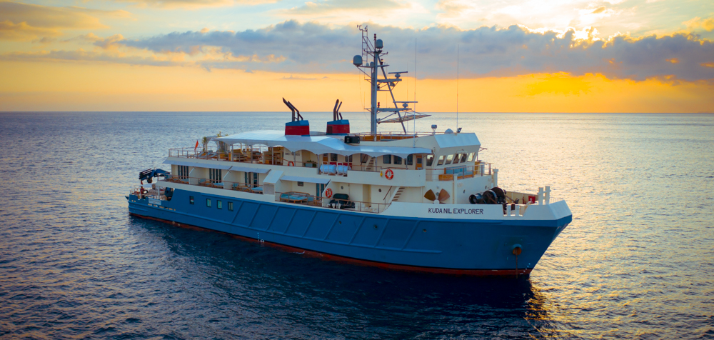 Kudanil Explorer sailing in blue water with a sunrise in the background from a yacht charter in Indonesia