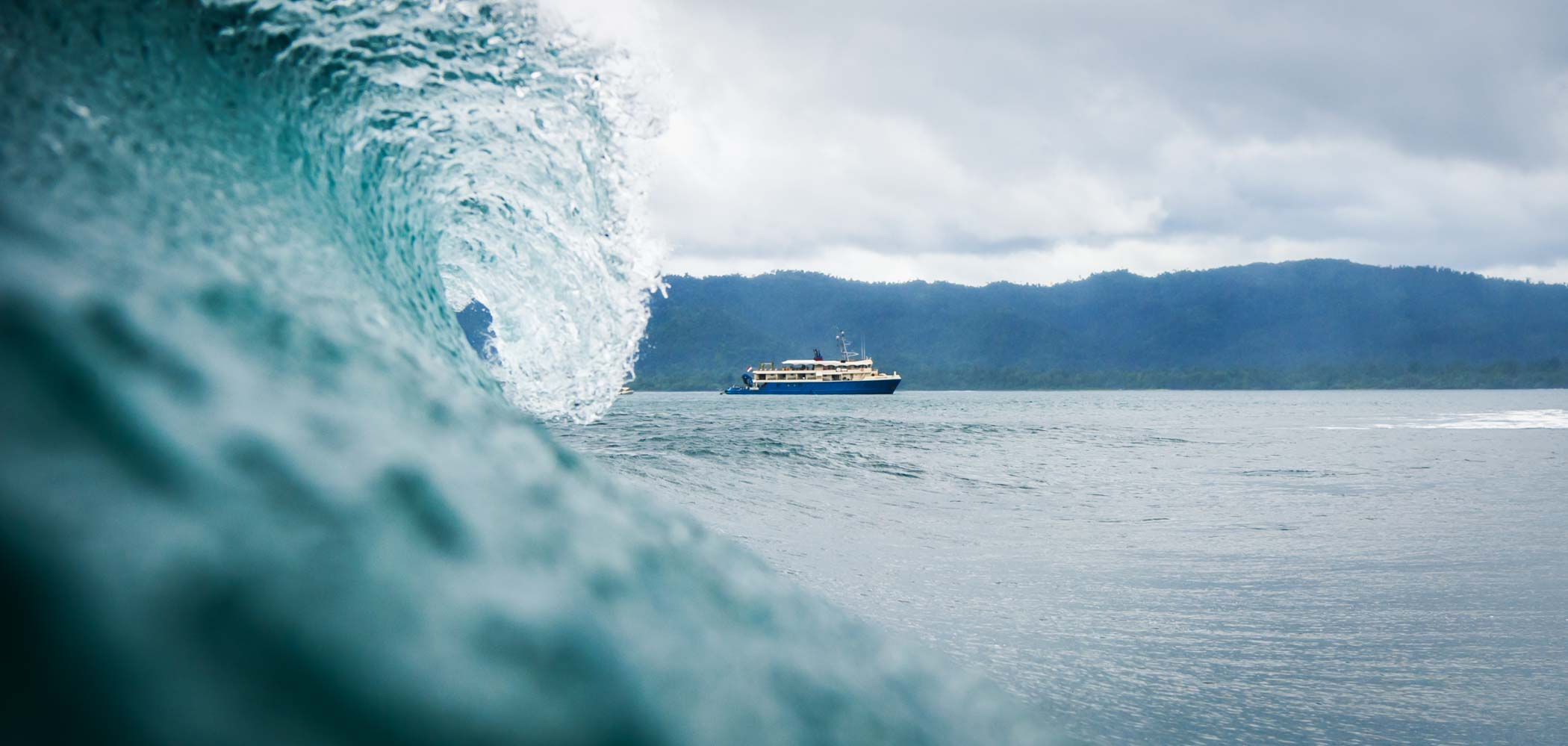 Wave crashing in the foreground with Kudanil Explorer in the background during a cloudy day