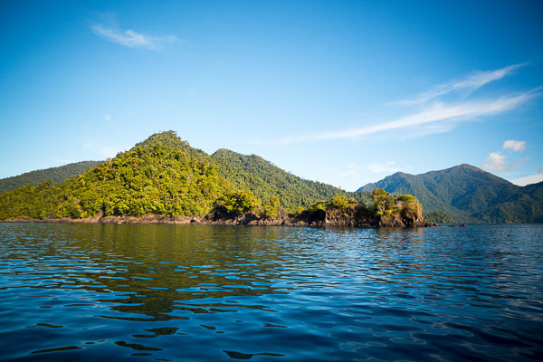 Green hills of the Tridacna Atoll surrounded by waters perfect for water sports set from a private yacht