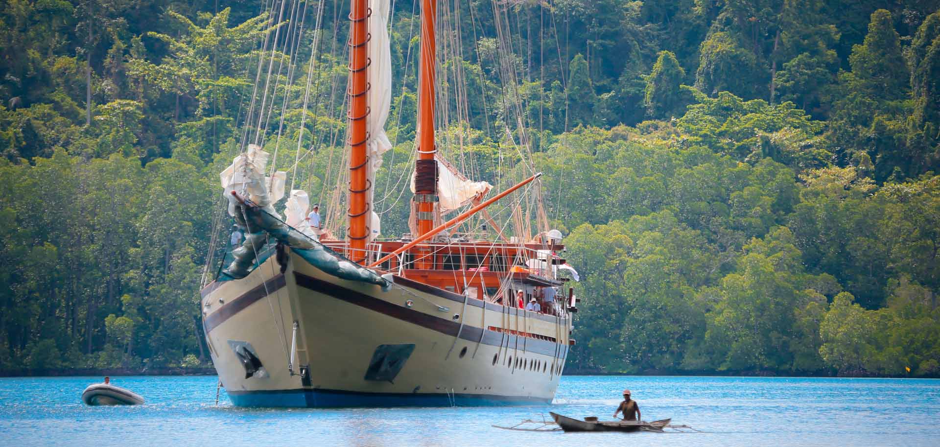 Lamima superyacht cruising in blue Indonesian waters, dominating over a RIB and a small Indonesian boat surrounding it