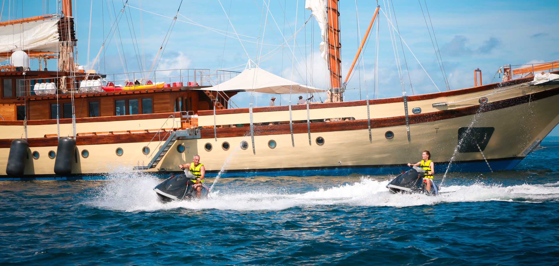 Yacht charter clients of Lamima superyacht enjoying a jet ski ride, with the yacht anchored in the background