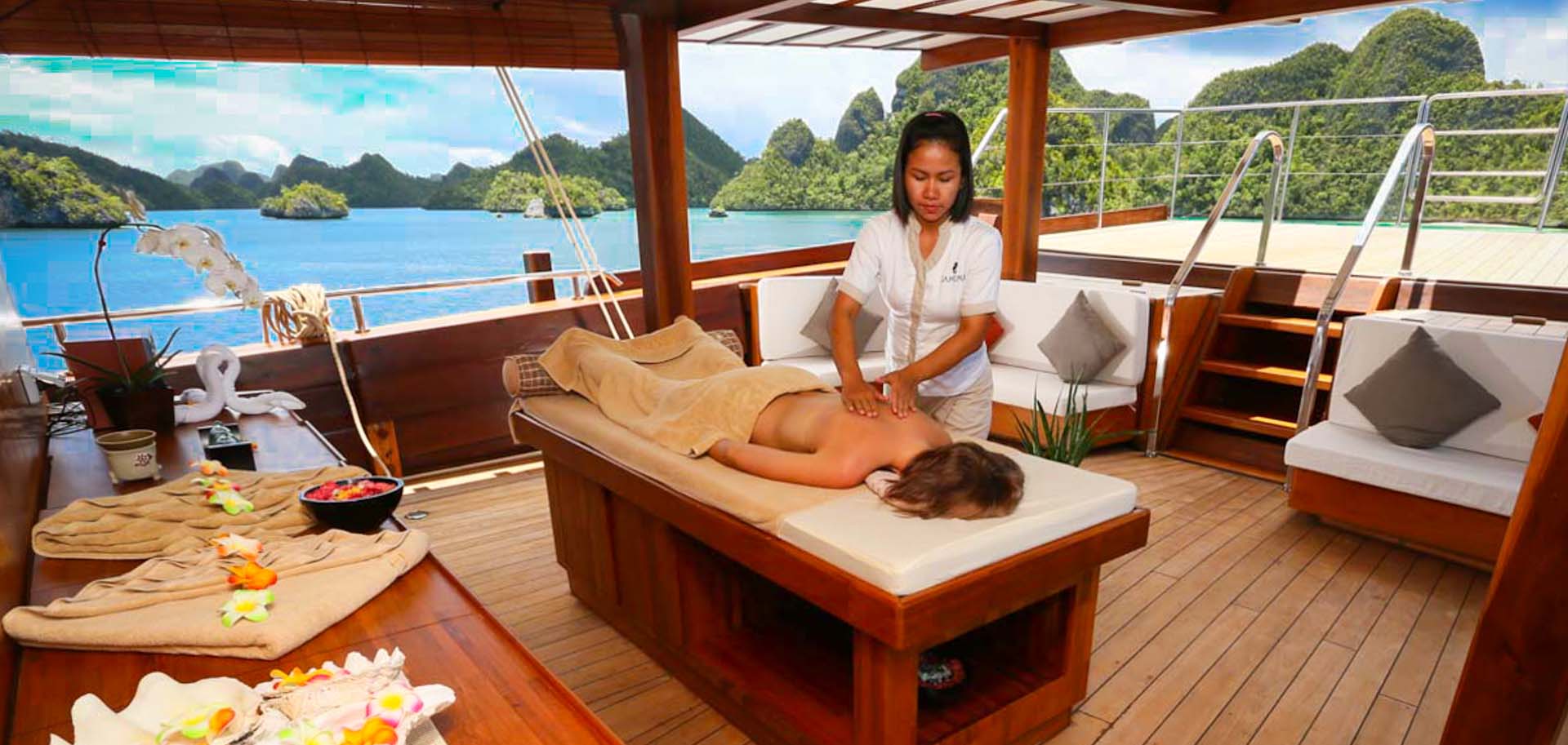 A masseuse performing a spa treatment on a yacht charter client on deck of Lamima superyacht